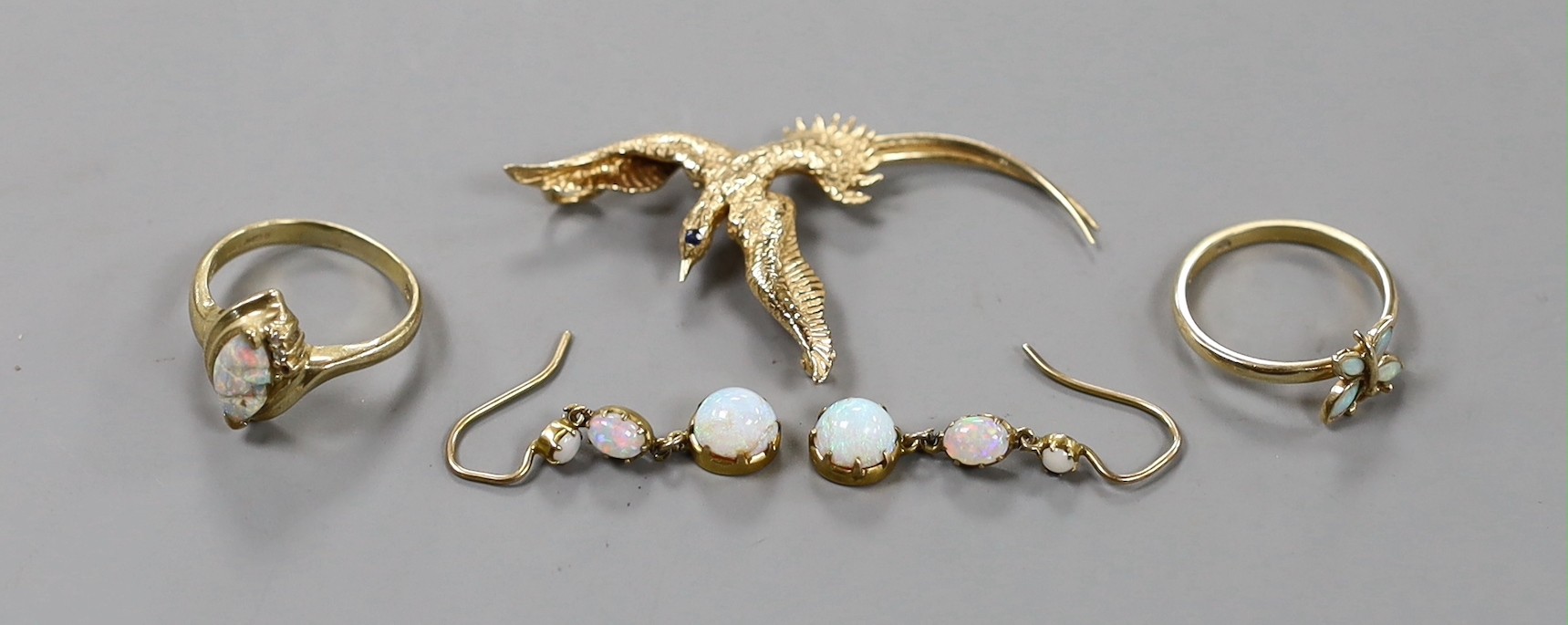 A 14k and gem set 'bird in flight' brooch, 50mm, gross weight 4.1 grams, a 9k and white opal ring, pair of yellow metal and white opal drop earrings and a yellow metal and white opal 'butterfly' ring, gross 6.4 grams.